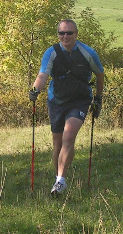 Nordic-Walking-Trainer mit Stöcken auf einer Wiese